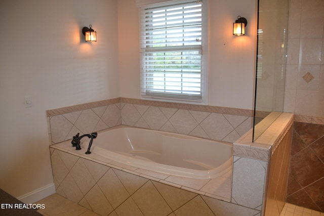 bathroom featuring a wealth of natural light, tile patterned floors, and a relaxing tiled tub