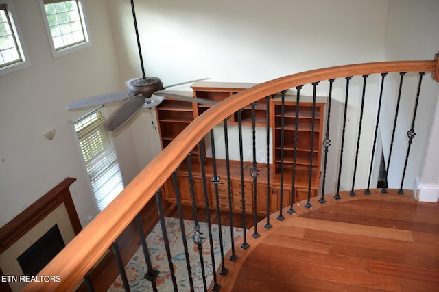 stairway featuring wood-type flooring, ceiling fan, and a brick fireplace