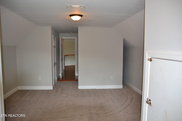 additional living space with light carpet and vaulted ceiling