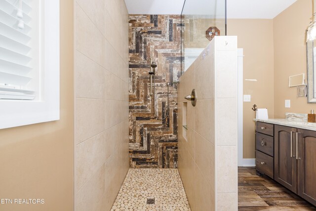 bathroom with wood-type flooring, vanity, and tiled shower