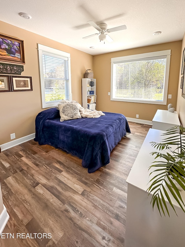 bedroom featuring hardwood / wood-style floors, ceiling fan, multiple windows, and a textured ceiling