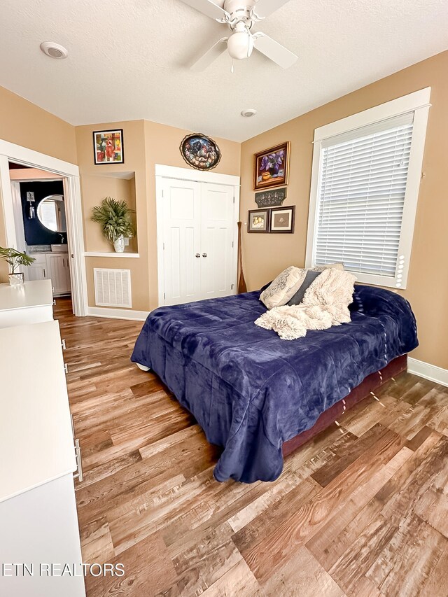 bedroom featuring a closet, a textured ceiling, ceiling fan, and light hardwood / wood-style flooring