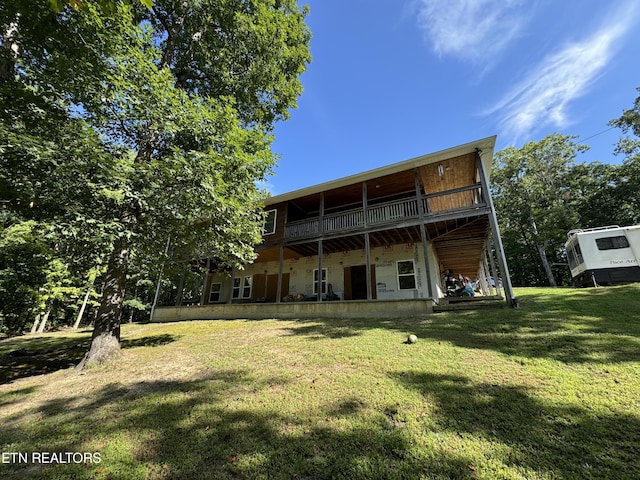 rear view of property featuring a deck and a lawn