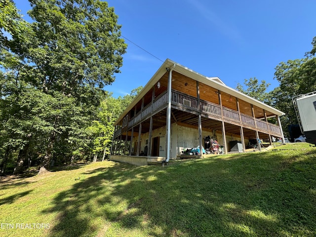 rear view of house with a lawn and a balcony