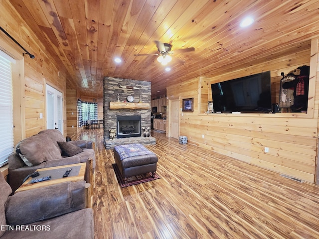 living room with wood walls, wood ceiling, visible vents, a ceiling fan, and wood finished floors