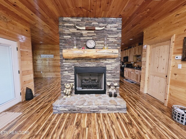 unfurnished living room with a fireplace, wood walls, wood ceiling, and light hardwood / wood-style flooring