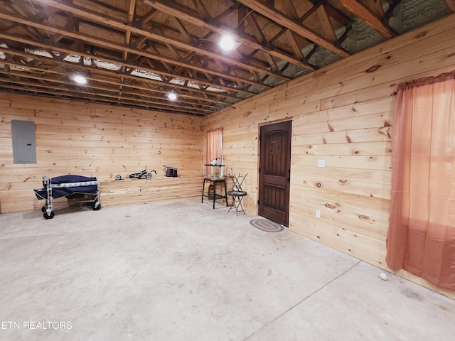 miscellaneous room with unfinished concrete floors, wooden walls, and electric panel