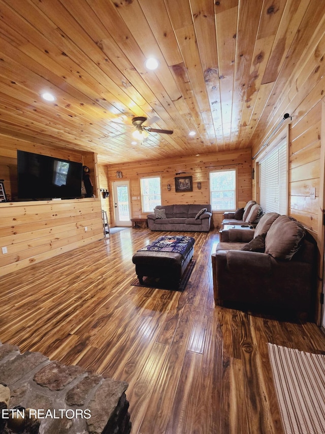 living room featuring a healthy amount of sunlight, wooden walls, wooden ceiling, and wood-type flooring
