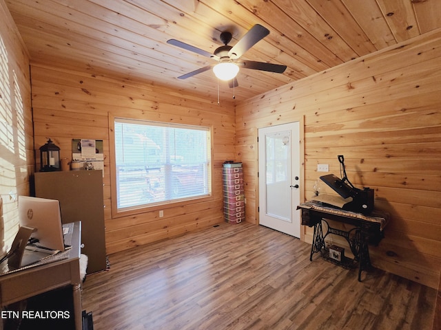 living area with a ceiling fan, wood ceiling, wooden walls, and wood finished floors