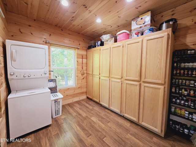 laundry area with light hardwood / wood-style floors, wood walls, stacked washer and dryer, and wood ceiling