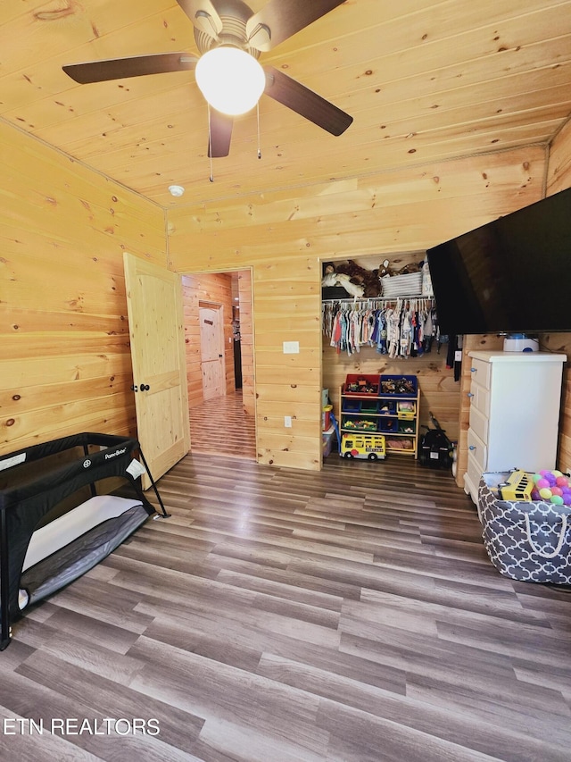 rec room featuring wooden ceiling, ceiling fan, wood finished floors, and wooden walls