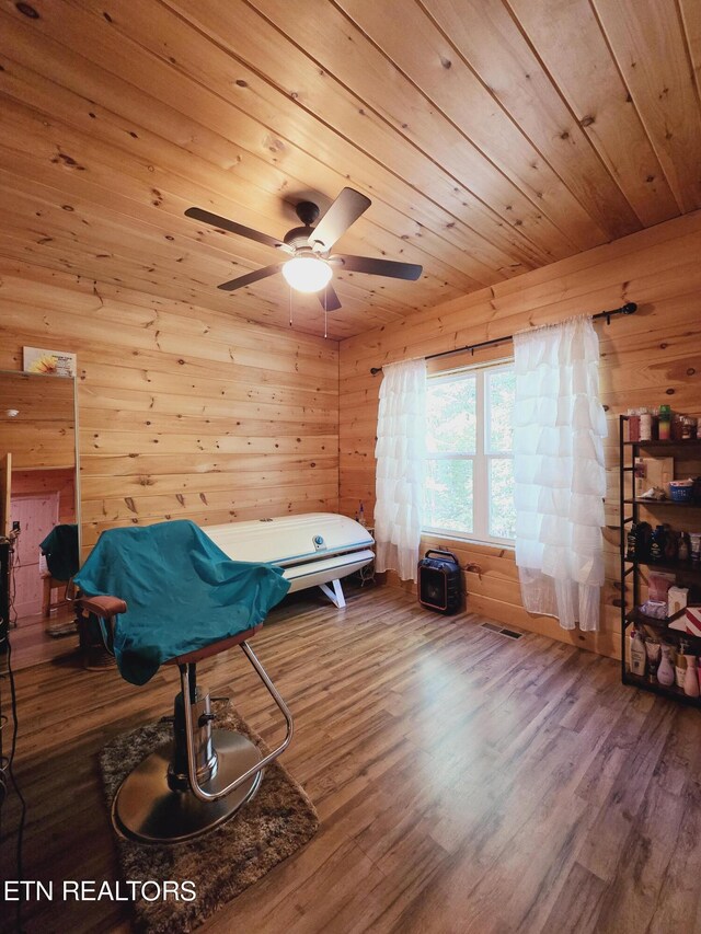 bedroom featuring wood-type flooring, wood ceiling, wooden walls, and ceiling fan