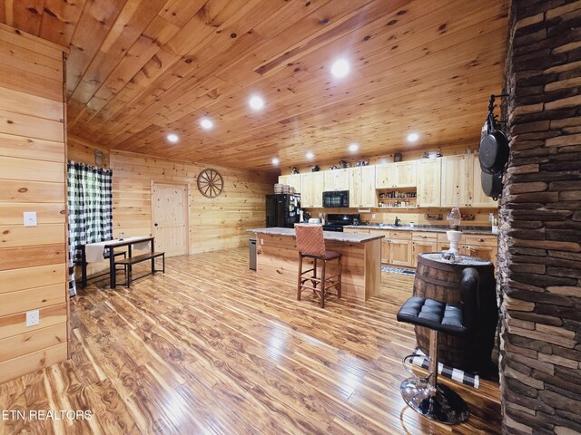 kitchen with wood ceiling, light hardwood / wood-style floors, a center island, a breakfast bar area, and black appliances