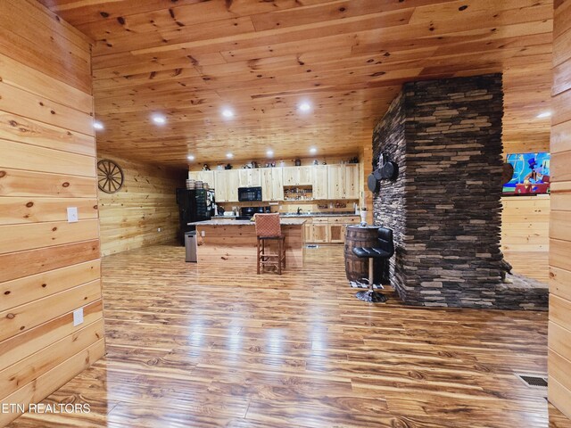 kitchen with a kitchen breakfast bar, wood ceiling, wood walls, light wood-type flooring, and a center island