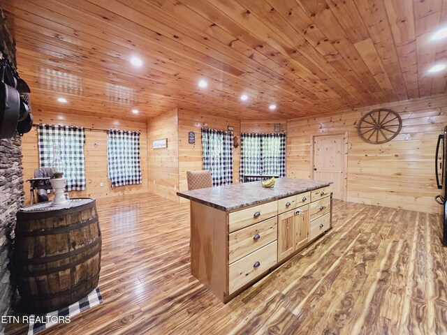 kitchen featuring light brown cabinets, wood walls, wooden ceiling, light wood-type flooring, and black refrigerator