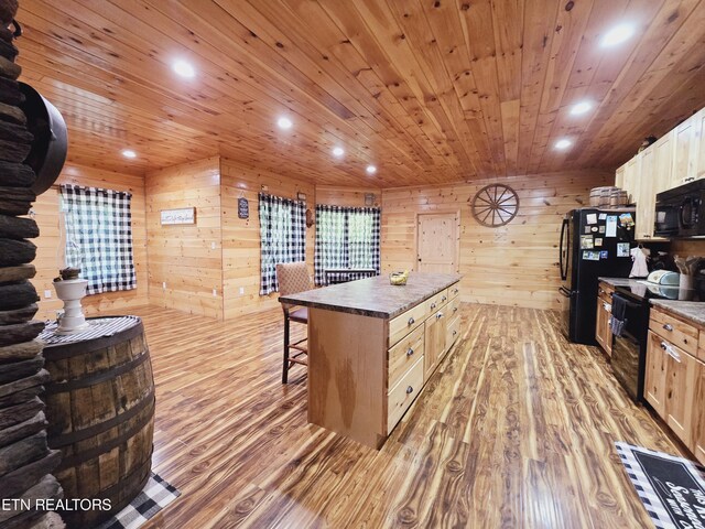 kitchen with a breakfast bar, light wood-type flooring, a center island, wood walls, and black appliances