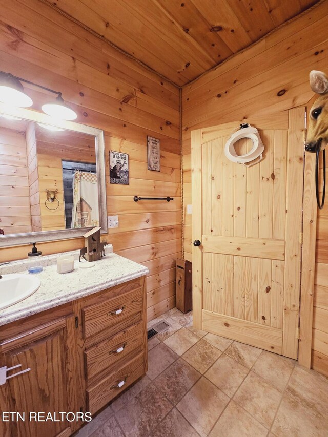 bathroom featuring vanity, wooden walls, tile patterned flooring, and wooden ceiling