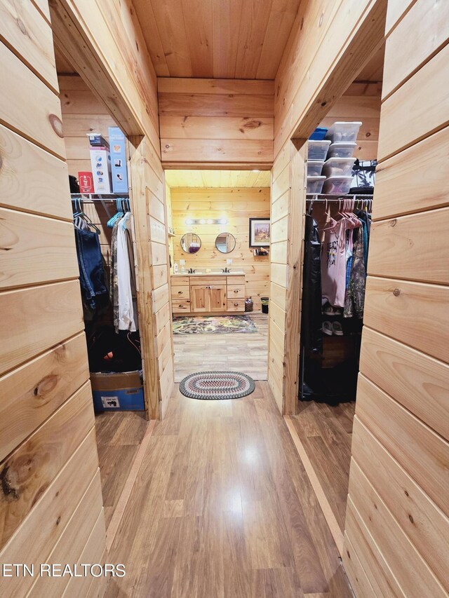 hall featuring wooden walls, wooden ceiling, and light hardwood / wood-style flooring