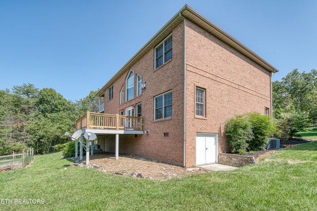 rear view of house featuring central AC unit, a yard, and a wooden deck