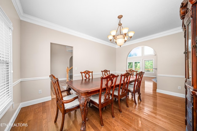 dining room with ornamental molding, light wood-type flooring, and a chandelier