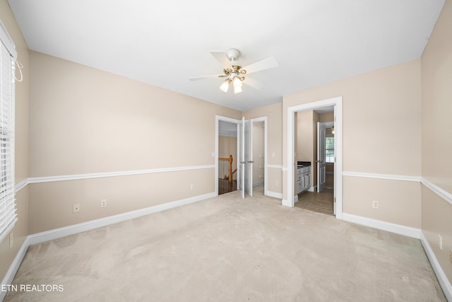 unfurnished bedroom with connected bathroom, ceiling fan, and light colored carpet