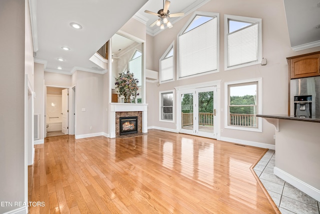 unfurnished living room with ceiling fan, light hardwood / wood-style flooring, a fireplace, and ornamental molding