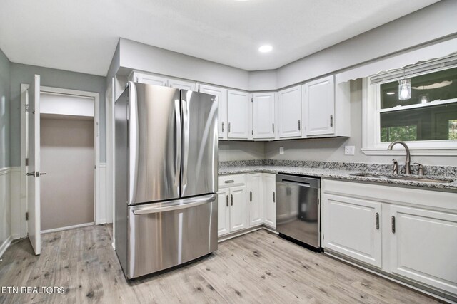 kitchen with stainless steel appliances, white cabinets, light hardwood / wood-style floors, and sink