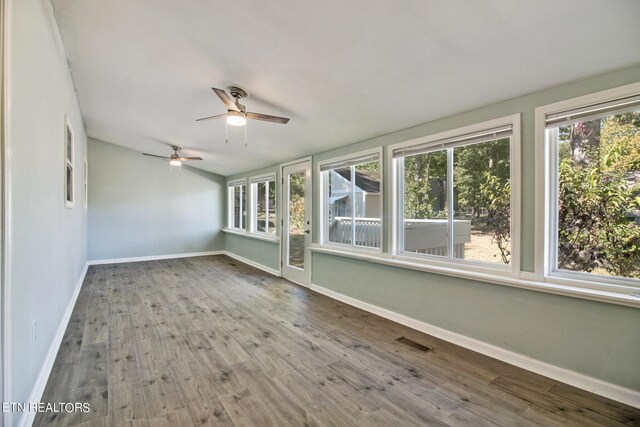 unfurnished sunroom featuring ceiling fan and plenty of natural light