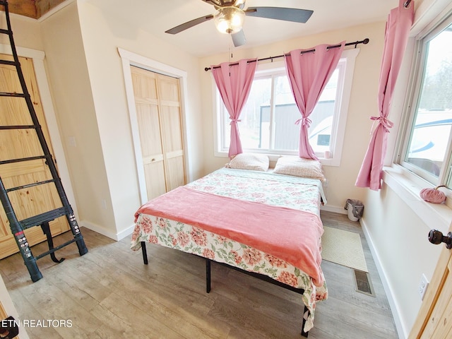 bedroom featuring multiple windows, light wood-type flooring, and a closet