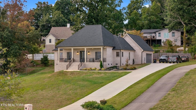 view of front of house with a garage, a porch, and a front lawn