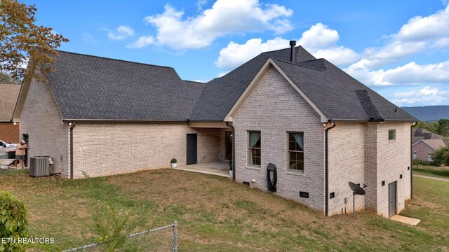 rear view of house with a patio, central air condition unit, and a yard