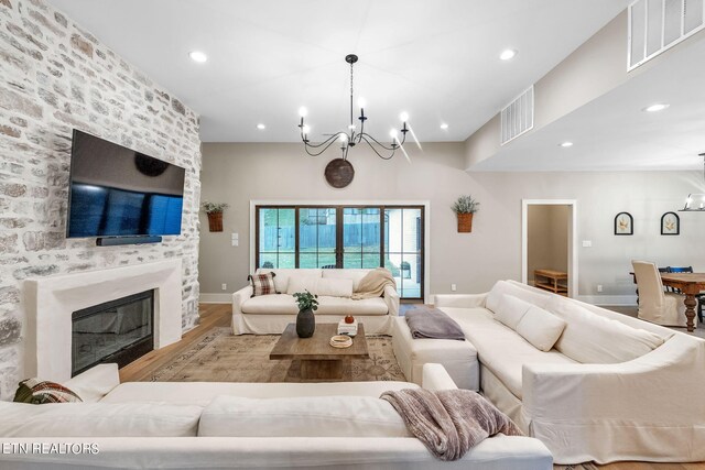 living room with a fireplace, an inviting chandelier, and light hardwood / wood-style flooring