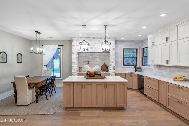 kitchen featuring hanging light fixtures, a kitchen island, light hardwood / wood-style flooring, and white cabinets