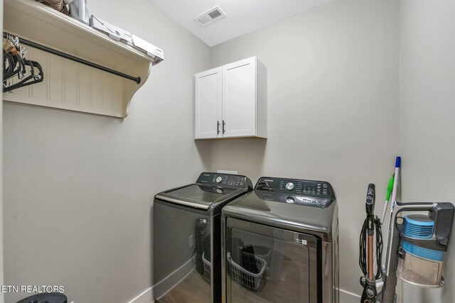 clothes washing area featuring washer and clothes dryer and cabinets