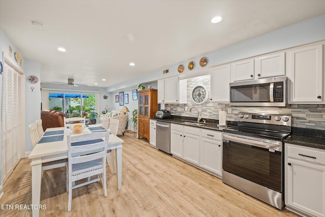 kitchen featuring light wood-type flooring, sink, white cabinets, stainless steel appliances, and ceiling fan