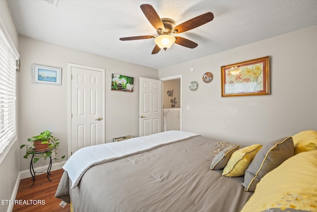 bedroom with ceiling fan, a textured ceiling, and dark hardwood / wood-style floors