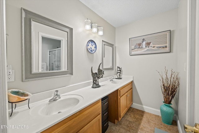 bathroom with vanity, an enclosed shower, a textured ceiling, and tile patterned floors