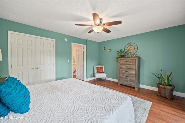 bedroom with a closet, ceiling fan, hardwood / wood-style floors, and a textured ceiling