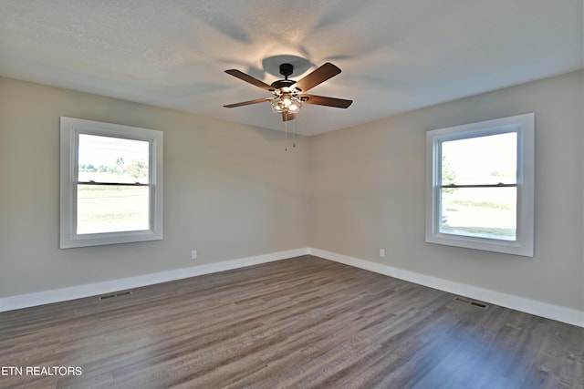 unfurnished room featuring dark wood-type flooring, ceiling fan, a healthy amount of sunlight, and a textured ceiling