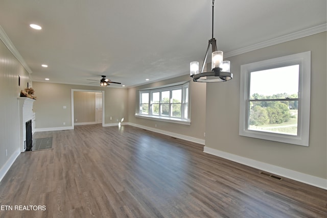 unfurnished living room featuring ceiling fan with notable chandelier, dark wood-type flooring, and crown molding