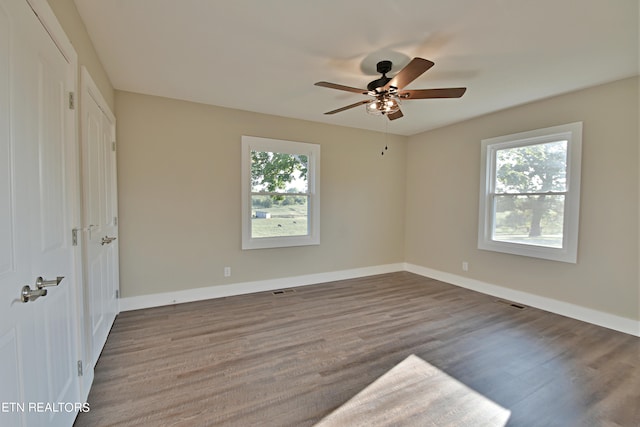 unfurnished bedroom featuring multiple windows, wood-type flooring, and ceiling fan