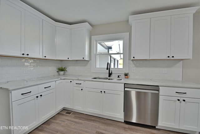 kitchen with light wood-type flooring, white cabinetry, sink, and stainless steel dishwasher