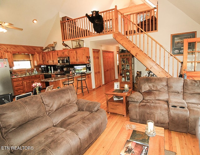 living room with high vaulted ceiling, sink, ceiling fan, and light hardwood / wood-style flooring