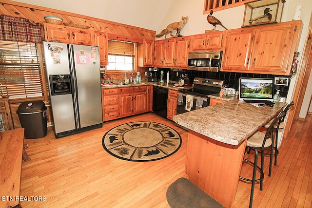 kitchen with light hardwood / wood-style floors, sink, a breakfast bar area, kitchen peninsula, and stainless steel appliances