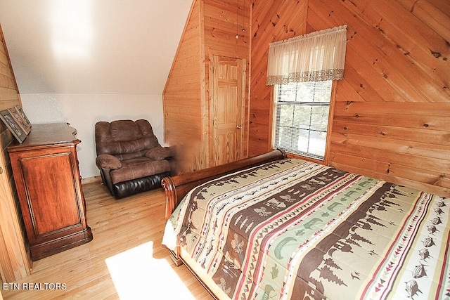 bedroom with light hardwood / wood-style floors, wood walls, and vaulted ceiling