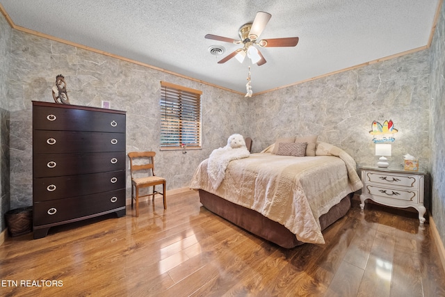 bedroom featuring a textured ceiling, hardwood / wood-style flooring, ceiling fan, and crown molding