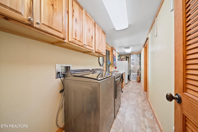 clothes washing area featuring light tile patterned floors, cabinets, and independent washer and dryer