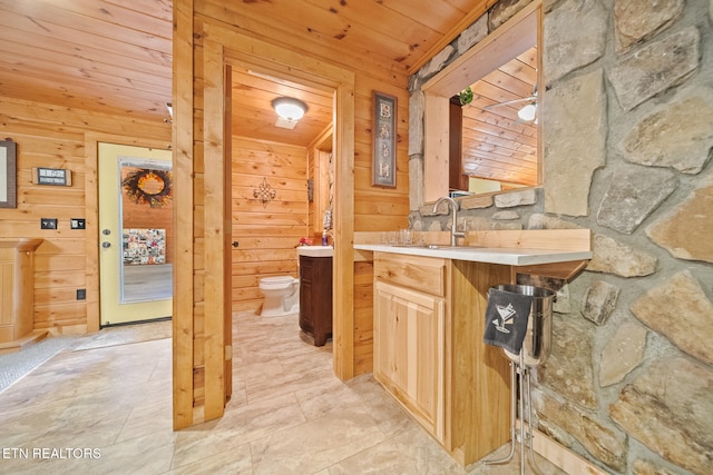 bathroom featuring vanity, toilet, wooden walls, and wood ceiling