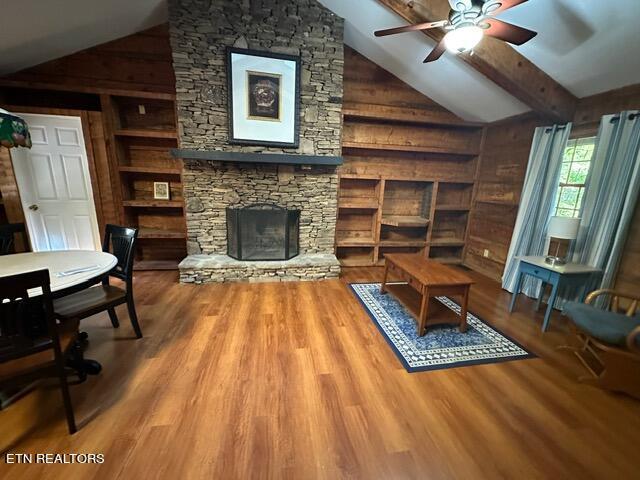 230 Penni Ln, Townsend, TN 37882 - living room with wooden walls, a ceiling fan, wood finished floors, a stone fireplace, and built in shelves