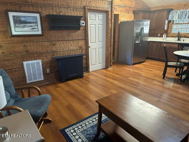 living room featuring wooden walls, sink, and light wood-type flooring